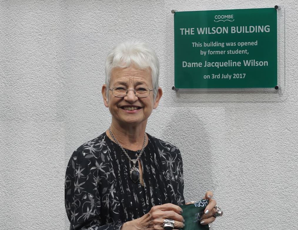 Dame Jacqueline Wilson posing next to the new building plaque at Coombe Girls' School